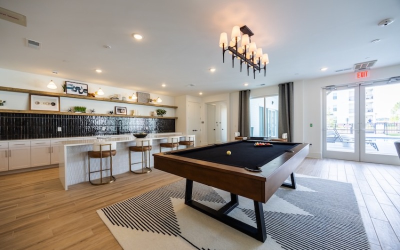 Stylish clubhouse with pool table, bar seating, and modern decor.