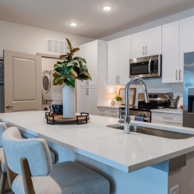 Relax and unwind in stylish living spaces Contemporary kitchen with white cabinets, stainless steel appliances, and island seating.